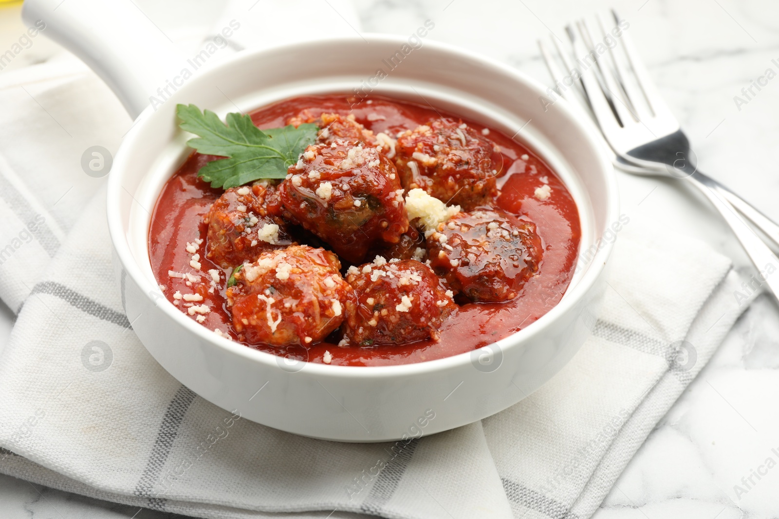 Photo of Delicious meatballs with tomato sauce, parmesan cheese and parsley served on white table, closeup