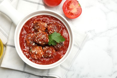 Photo of Delicious meatballs with tomato sauce, parmesan cheese and parsley served on white marble table, top view