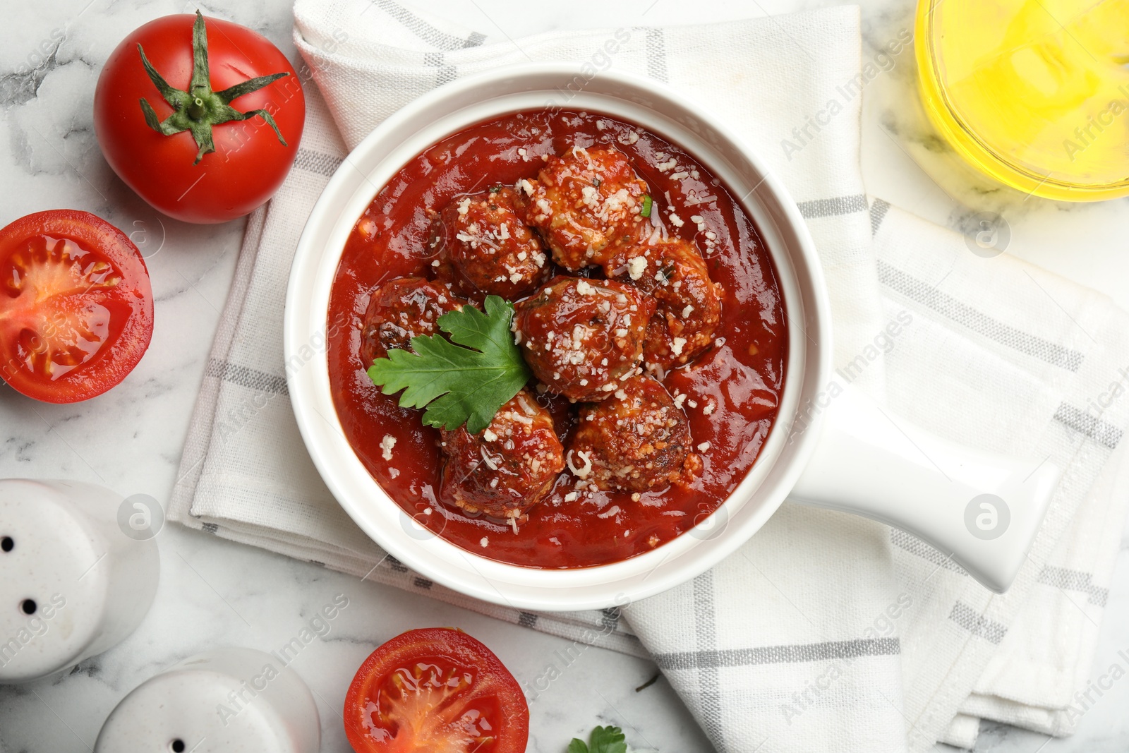 Photo of Delicious meatballs with tomato sauce, parmesan cheese and parsley served on white table, flat lay