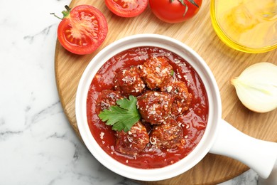 Photo of Delicious meatballs with tomato sauce, parmesan cheese and parsley served on white marble table, flat lay