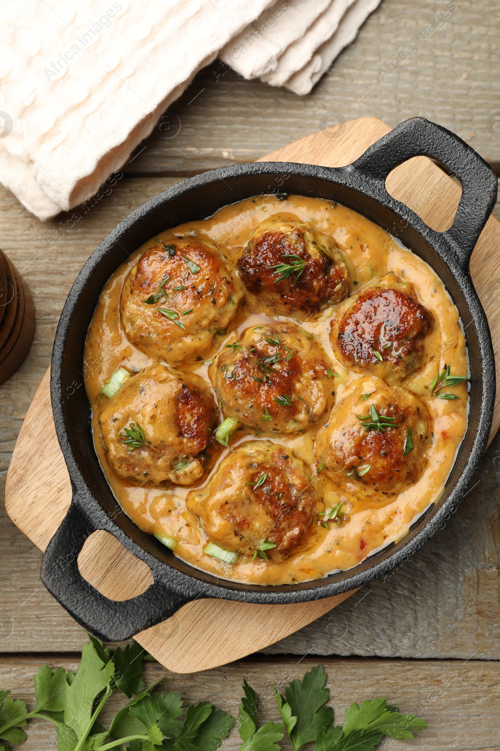 Photo of Delicious meatballs with gravy cream sauce and herbs on wooden table, flat lay