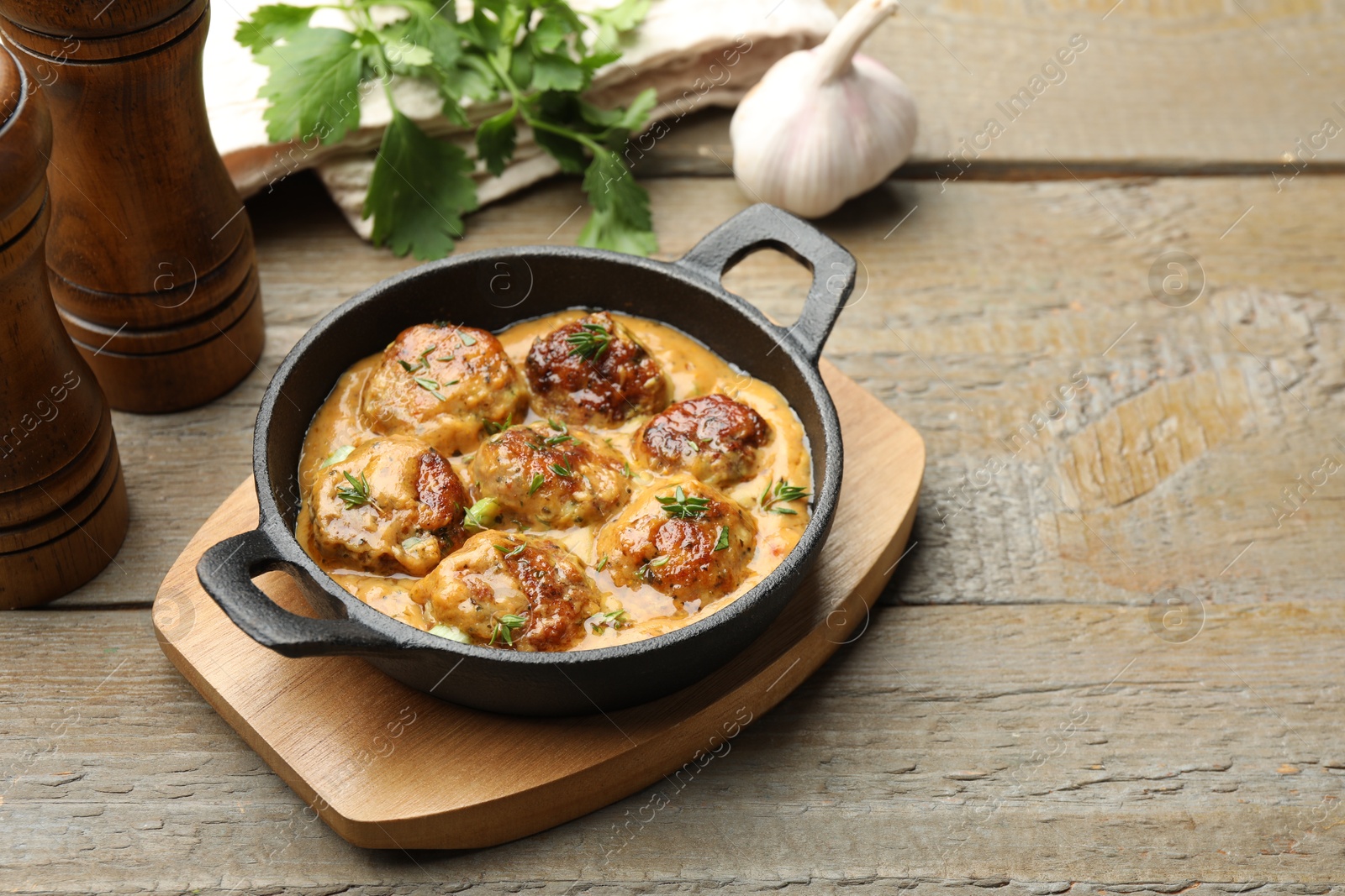 Photo of Delicious meatballs with gravy cream sauce and herbs on wooden table