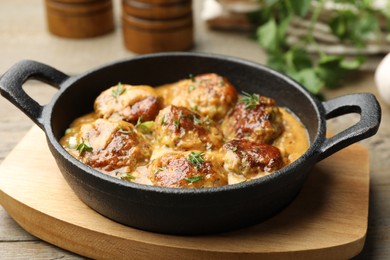 Photo of Delicious meatballs with gravy cream sauce and herbs on wooden table, closeup