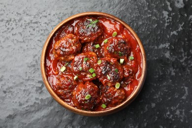 Photo of Delicious meatballs with tomato sauce and herbs on black table, top view