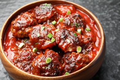 Photo of Delicious meatballs with tomato sauce and herbs on black table, closeup