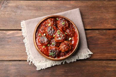 Photo of Delicious meatballs with tomato sauce and herbs on wooden table, top view