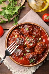 Photo of Delicious meatballs with tomato sauce and herbs served on wooden table, flat lay