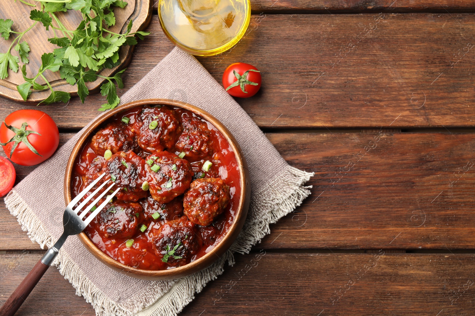 Photo of Delicious meatballs with tomato sauce and herbs served on wooden table, flat lay. Space for text