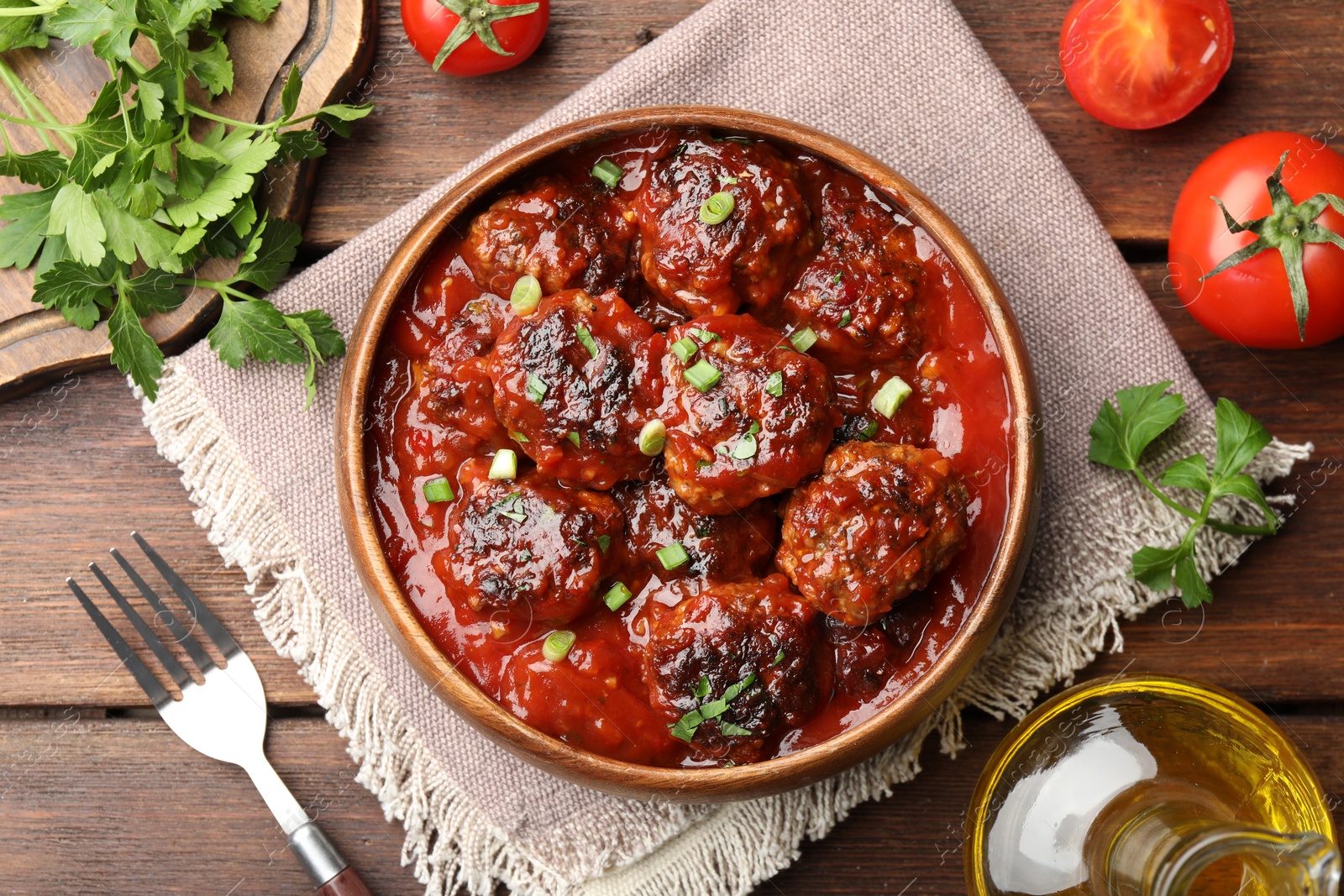 Photo of Delicious meatballs with tomato sauce and herbs served on wooden table, flat lay