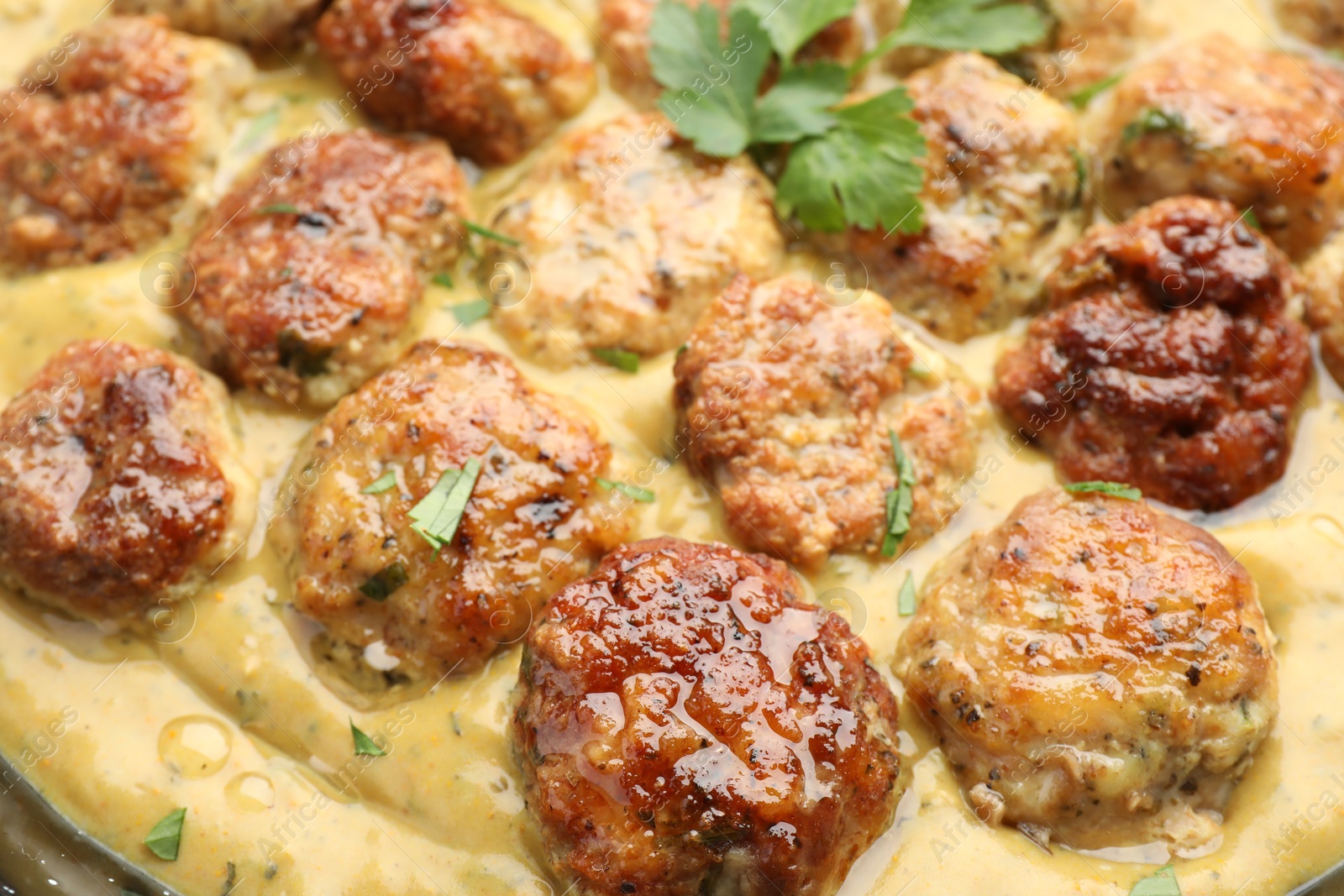 Photo of Delicious meatballs with gravy cream sauce and herbs, closeup