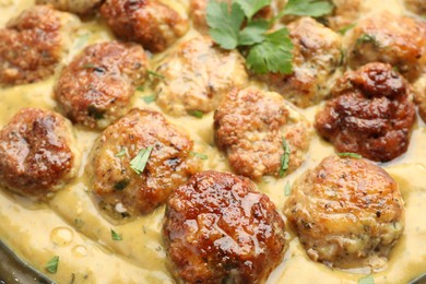 Photo of Delicious meatballs with gravy cream sauce and herbs, closeup