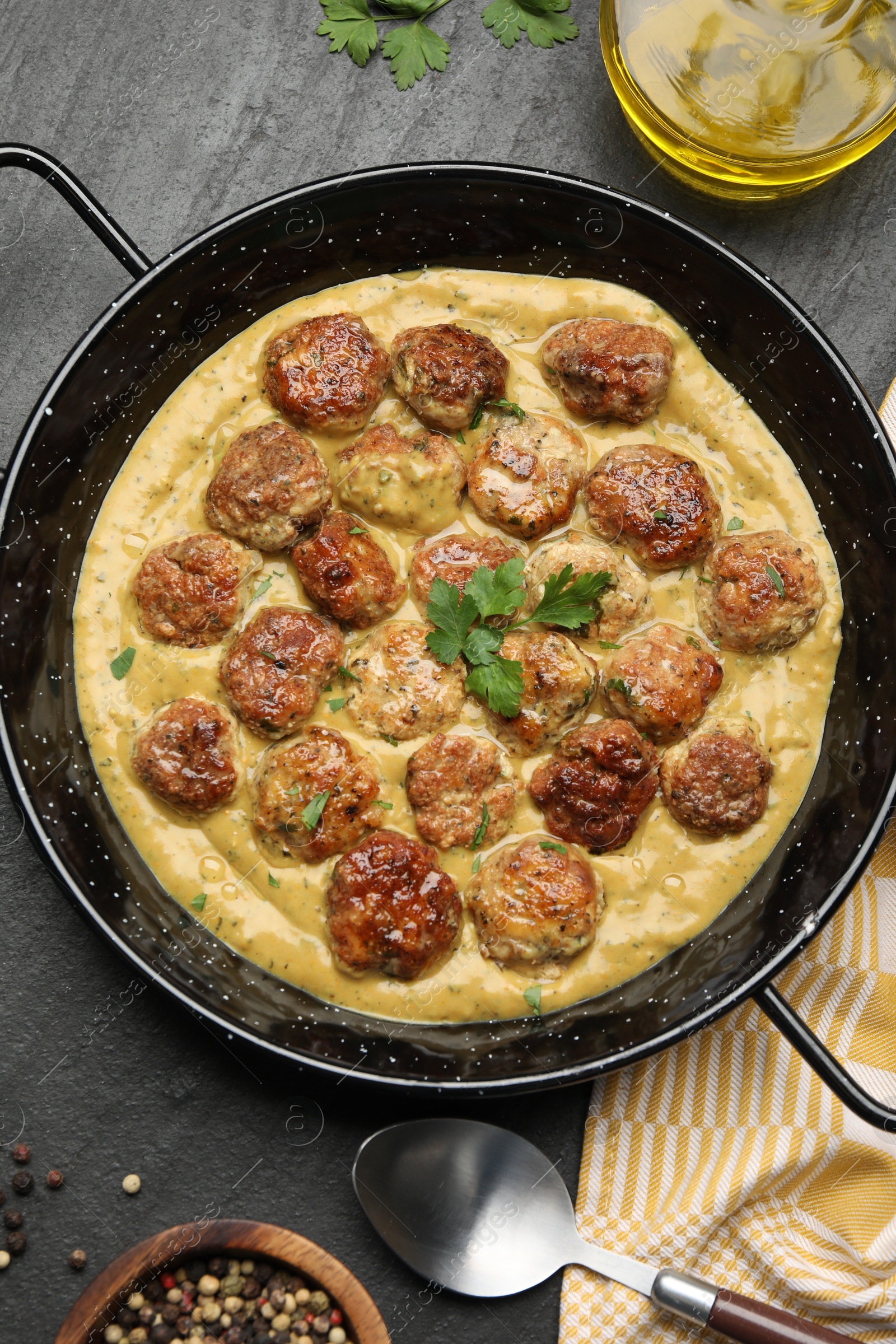 Photo of Delicious meatballs with gravy cream sauce and herbs served on black table, flat lay