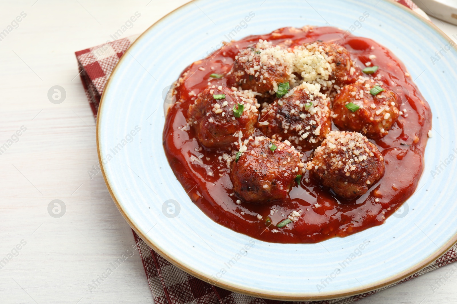 Photo of Delicious meatballs with tomato sauce, parmesan and herbs in on white wooden table, closeup