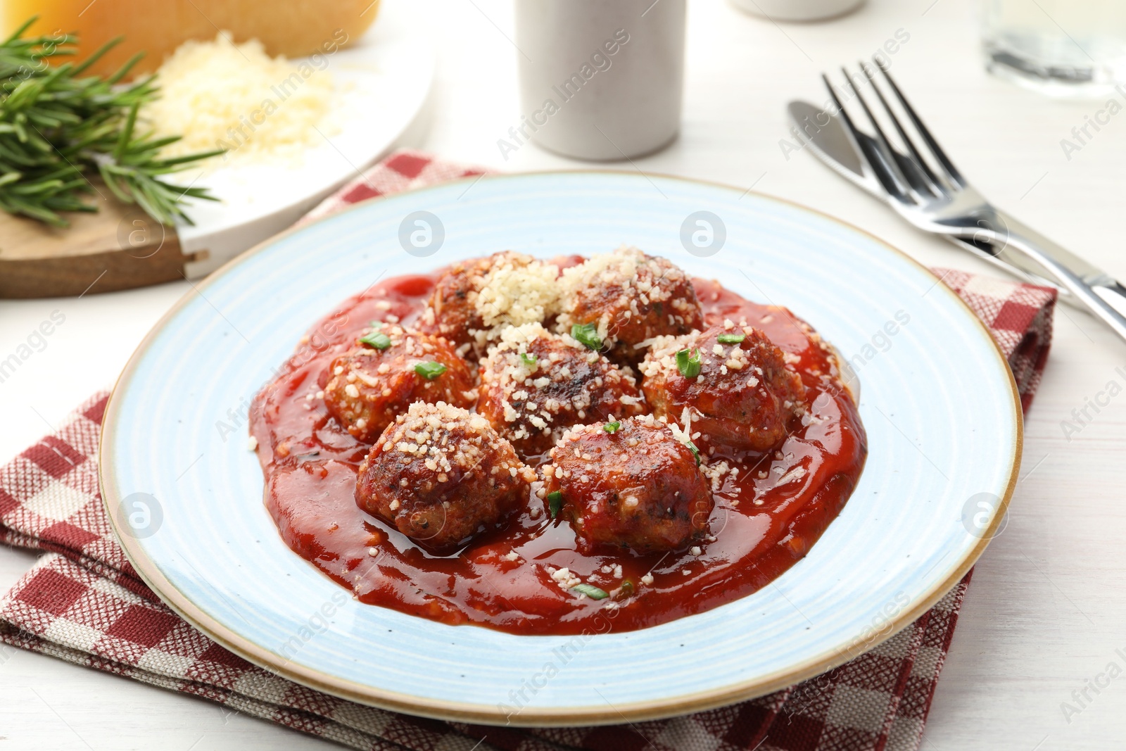 Photo of Delicious meatballs with tomato sauce, parmesan and herbs in served on white wooden table, closeup