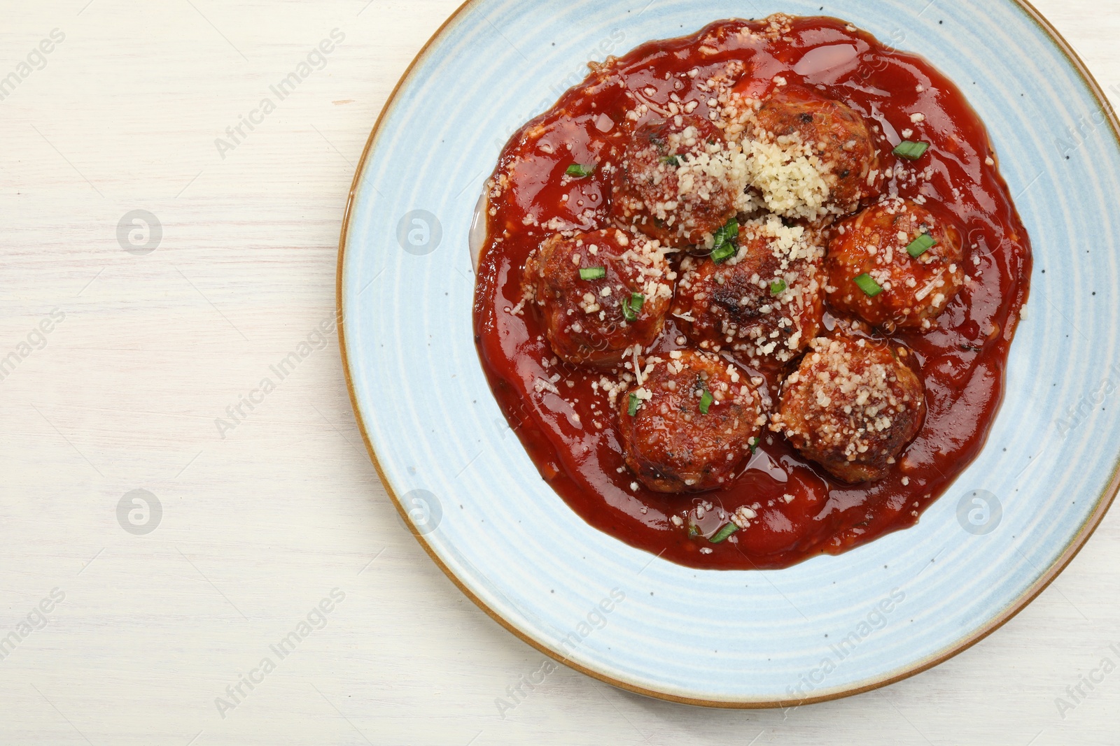 Photo of Delicious meatballs with tomato sauce, parmesan and herbs in on white wooden table, top view