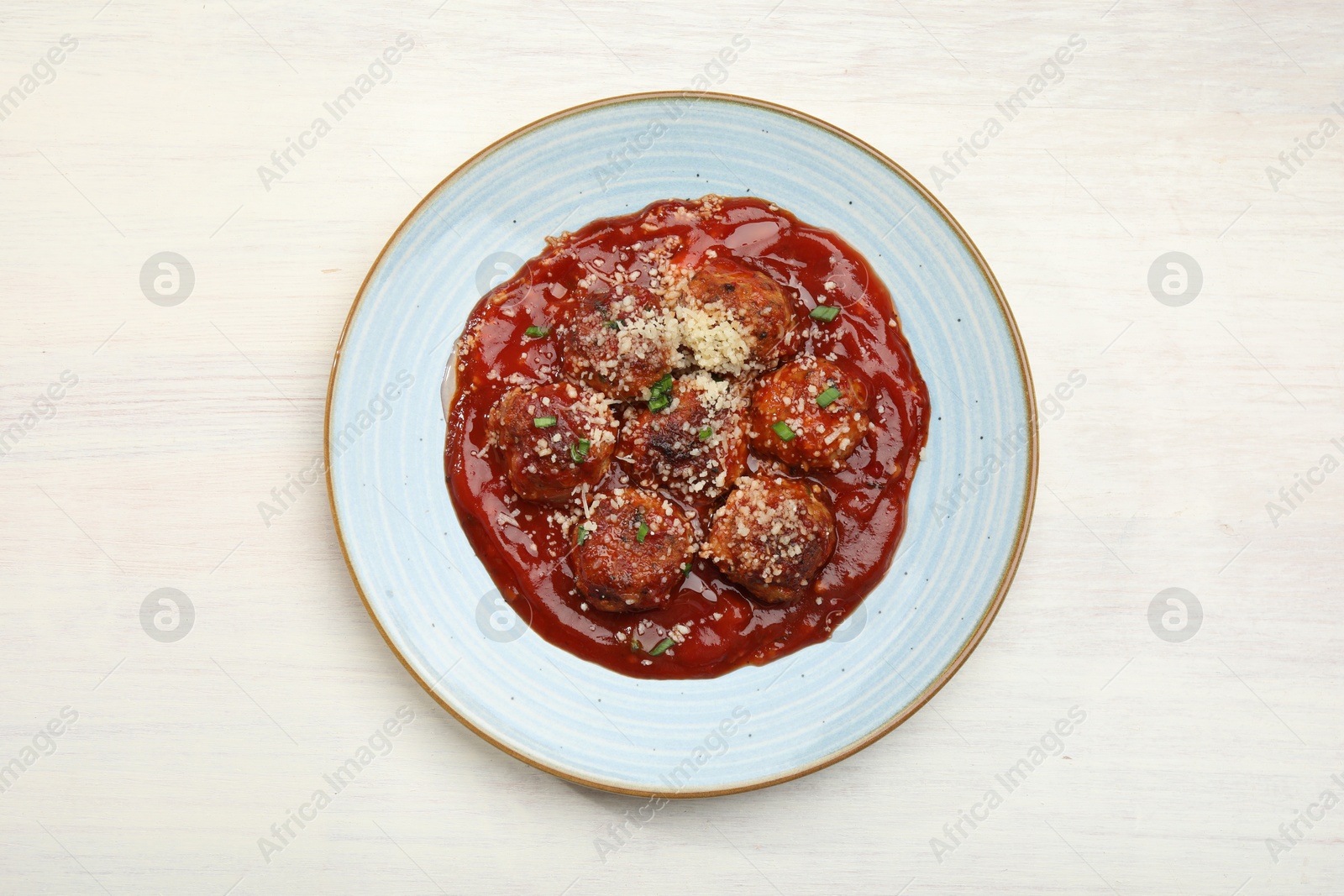 Photo of Delicious meatballs with tomato sauce, parmesan and herbs in on white wooden table, top view