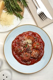 Photo of Delicious meatballs with tomato sauce, parmesan and herbs in served on white wooden table, flat lay