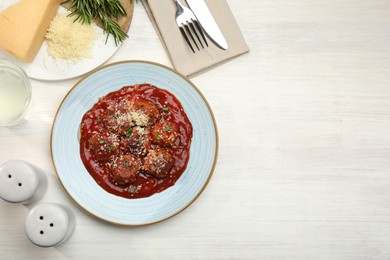 Photo of Delicious meatballs with tomato sauce, parmesan and herbs in served on white wooden table, flat lay. Space for text