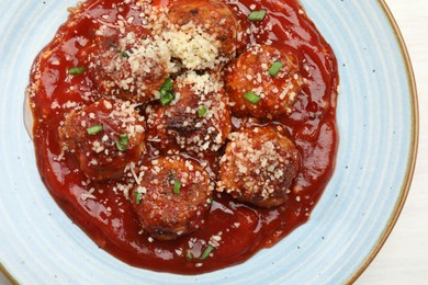 Photo of Delicious meatballs with tomato sauce, parmesan and herbs in on white wooden table, top view