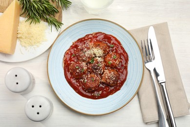 Photo of Delicious meatballs with tomato sauce, parmesan and herbs in served on white wooden table, flat lay