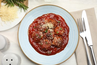 Photo of Delicious meatballs with tomato sauce, parmesan and herbs in served on white wooden table, flat lay