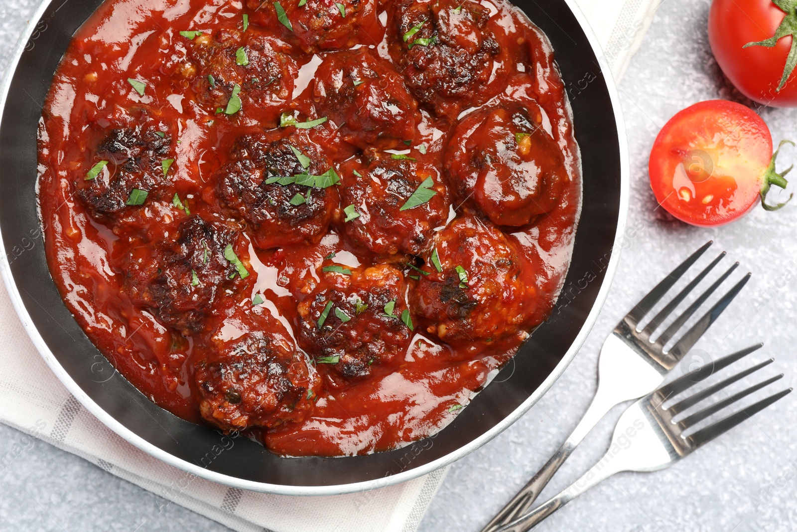 Photo of Delicious meatballs with tomato sauce and herbs in served on grey table, flat lay