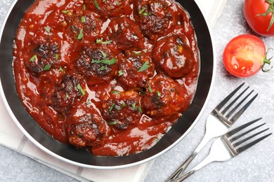 Photo of Delicious meatballs with tomato sauce and herbs in served on grey table, flat lay