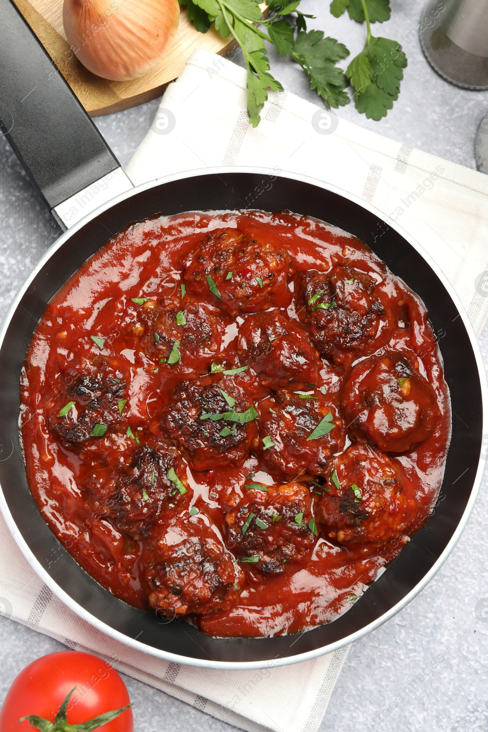 Photo of Delicious meatballs with tomato sauce and herbs in served on grey table, flat lay