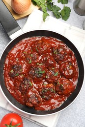 Photo of Delicious meatballs with tomato sauce and herbs in served on grey table, flat lay