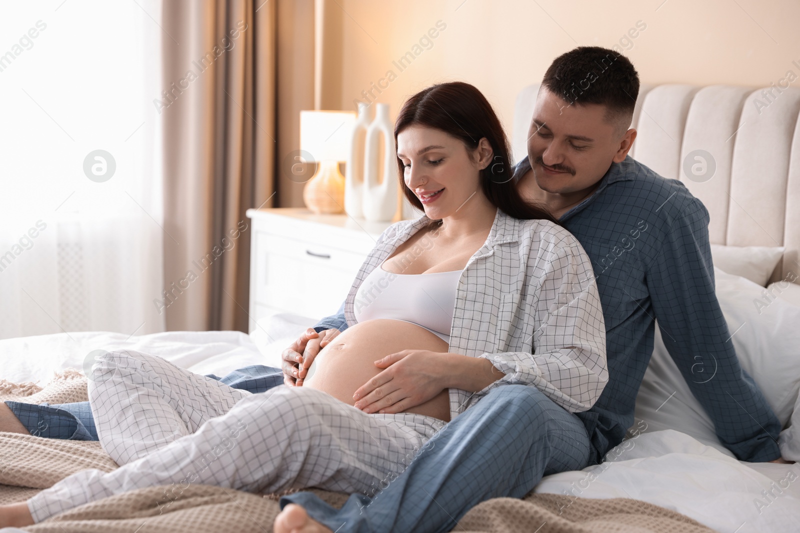 Photo of Pregnant woman and her husband on bed at home