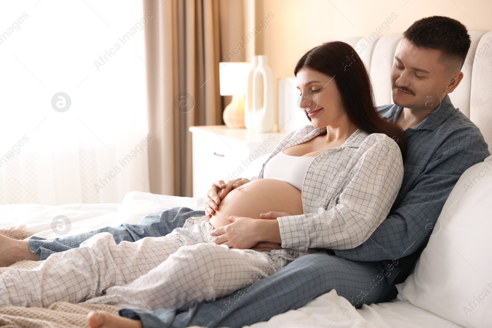 Photo of Pregnant woman and her husband on bed at home