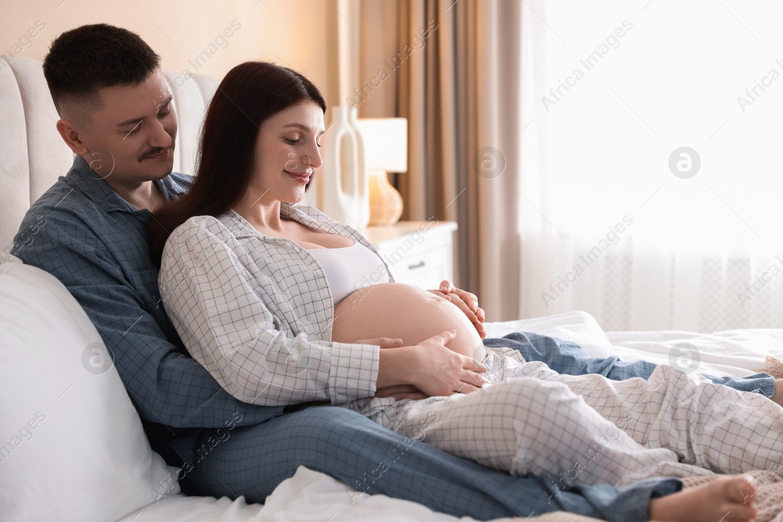 Photo of Pregnant woman and her husband on bed at home