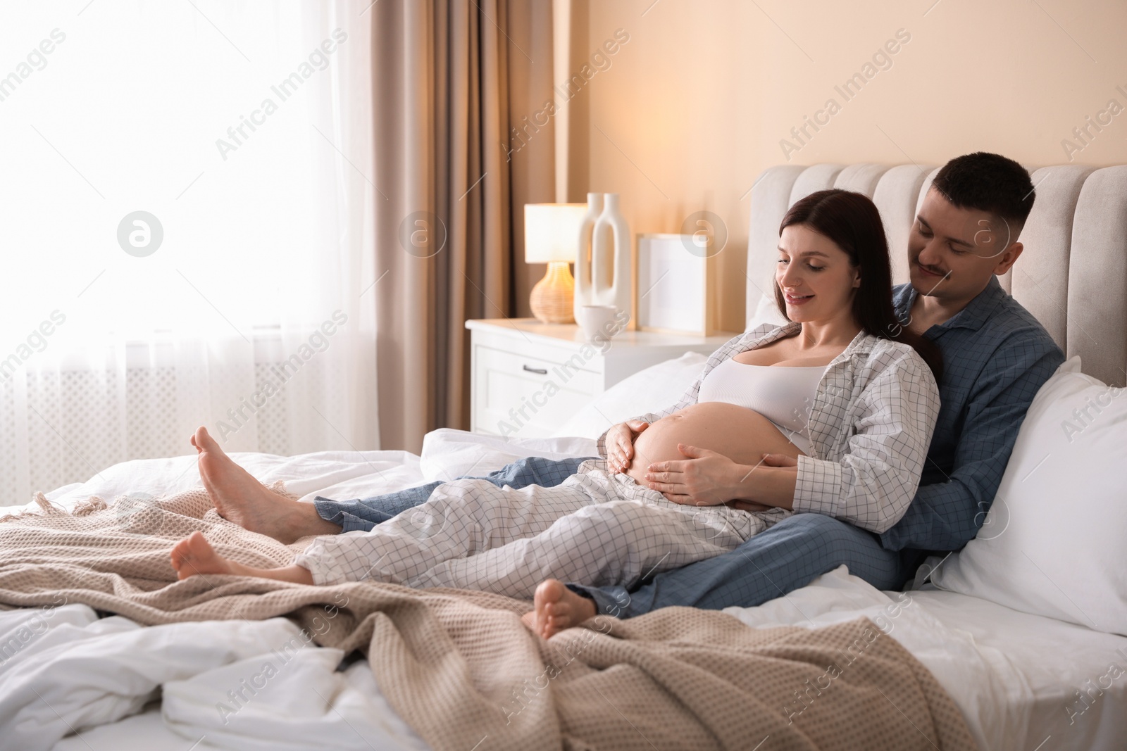 Photo of Pregnant woman and her husband on bed at home