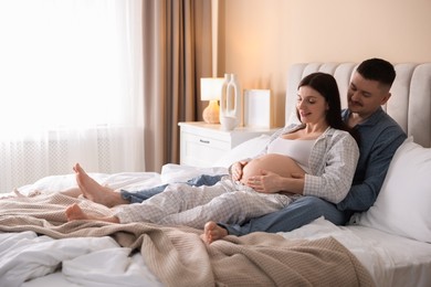 Photo of Pregnant woman and her husband on bed at home