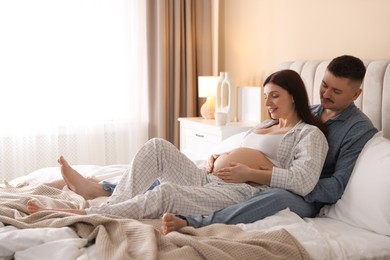 Photo of Pregnant woman and her husband on bed at home