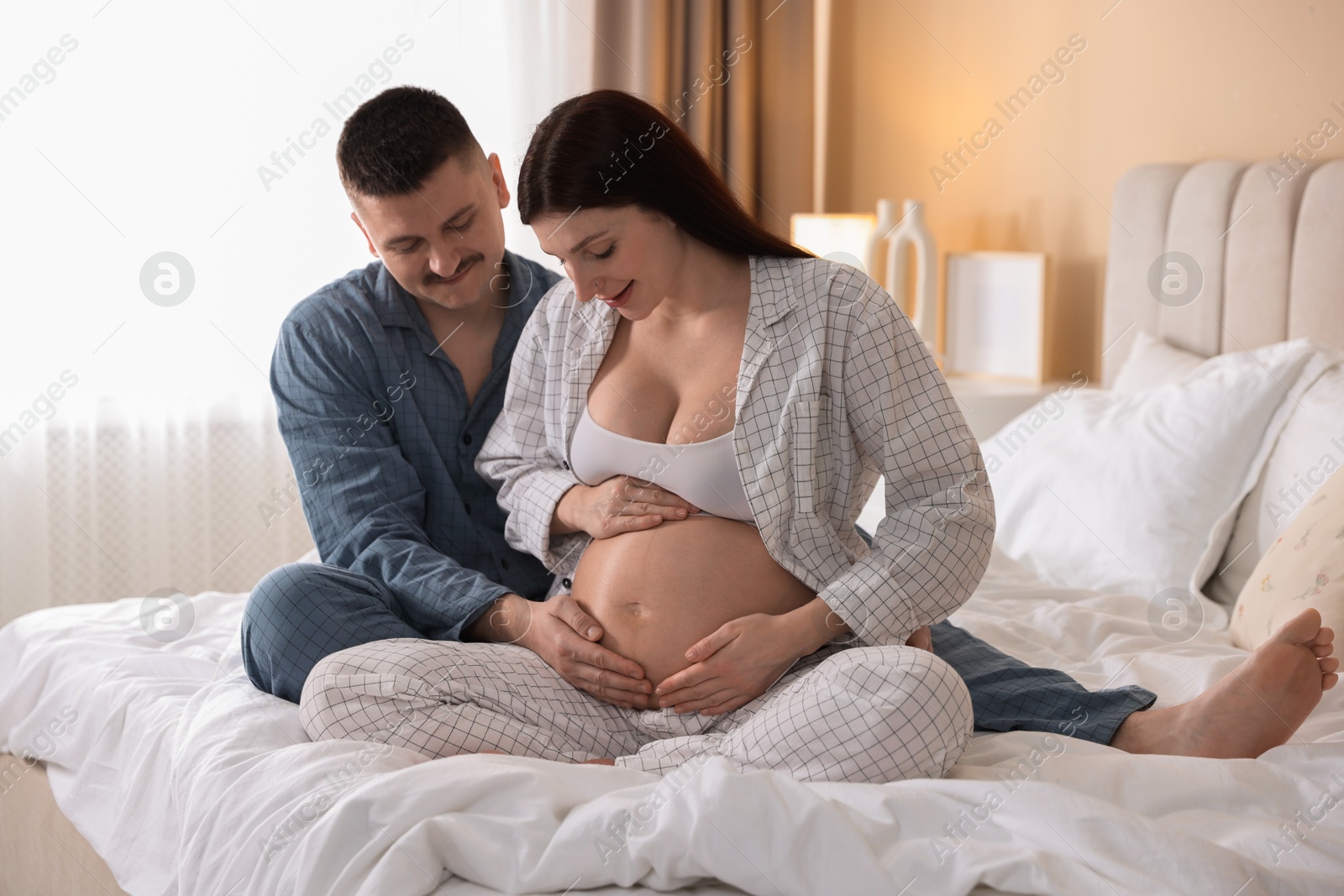 Photo of Pregnant woman and her husband on bed at home