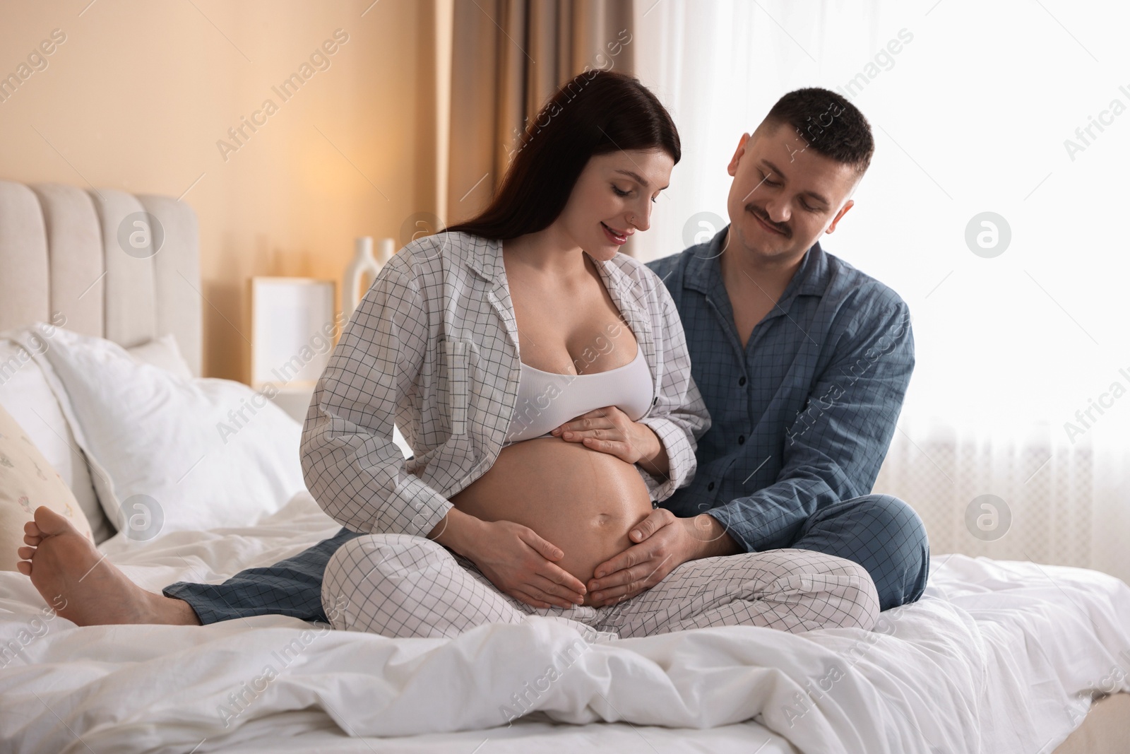 Photo of Pregnant woman and her husband on bed at home