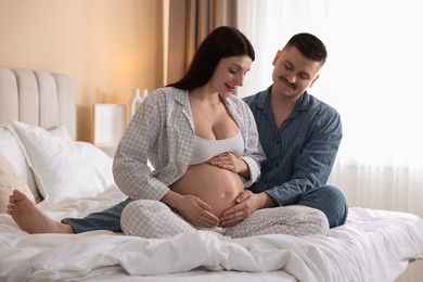 Photo of Pregnant woman and her husband on bed at home