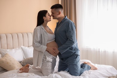 Pregnant woman and her husband on bed at home