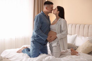 Photo of Pregnant woman and her husband on bed at home