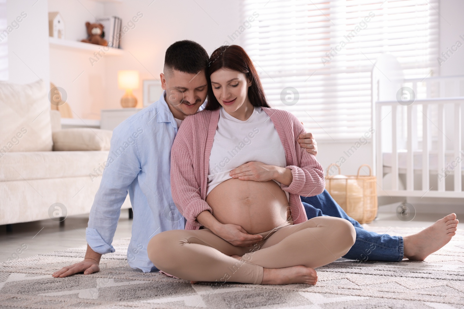 Photo of Pregnant woman and her husband on floor at home