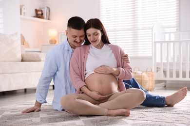 Photo of Pregnant woman and her husband on floor at home