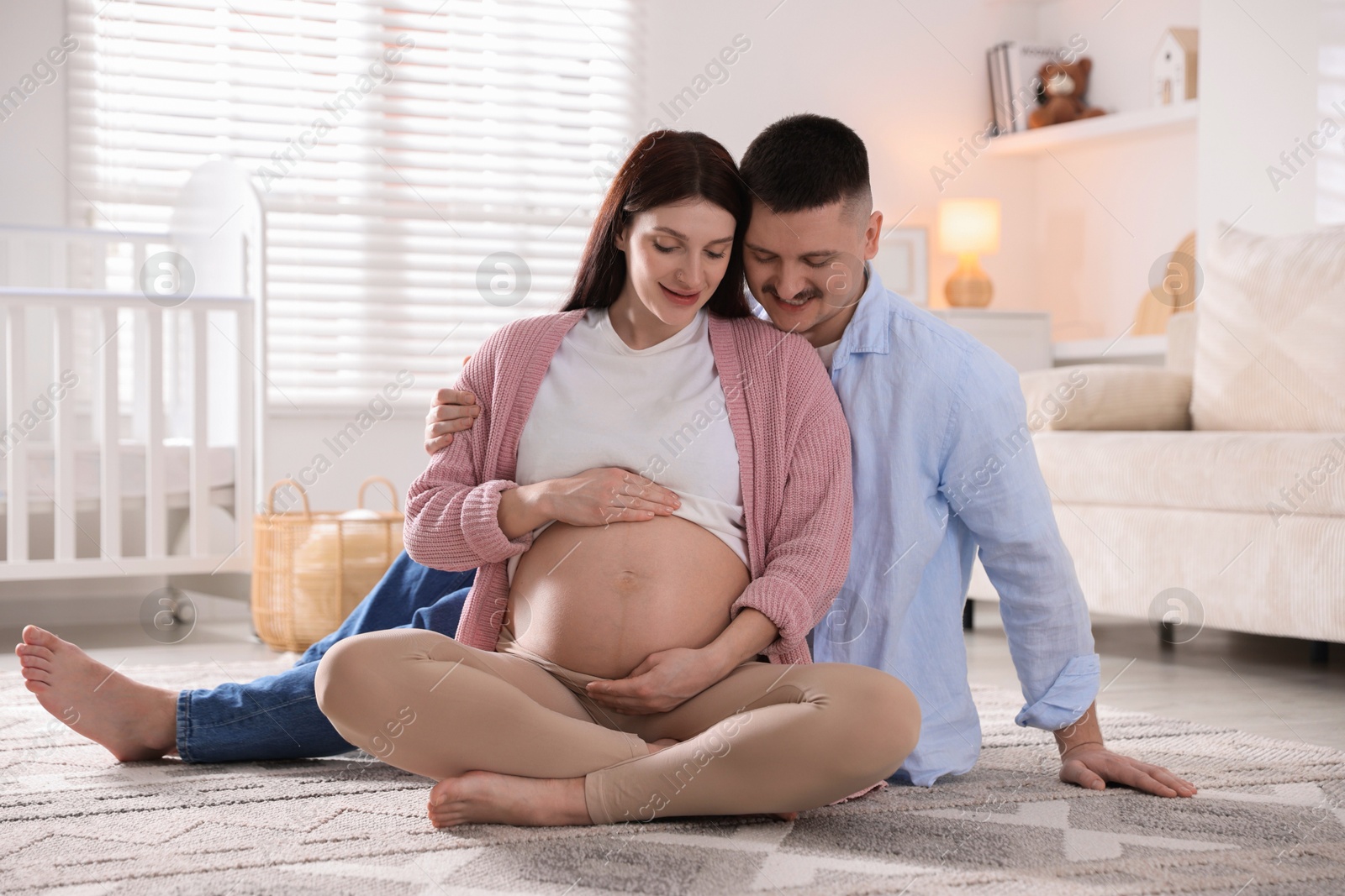 Photo of Pregnant woman and her husband on floor at home