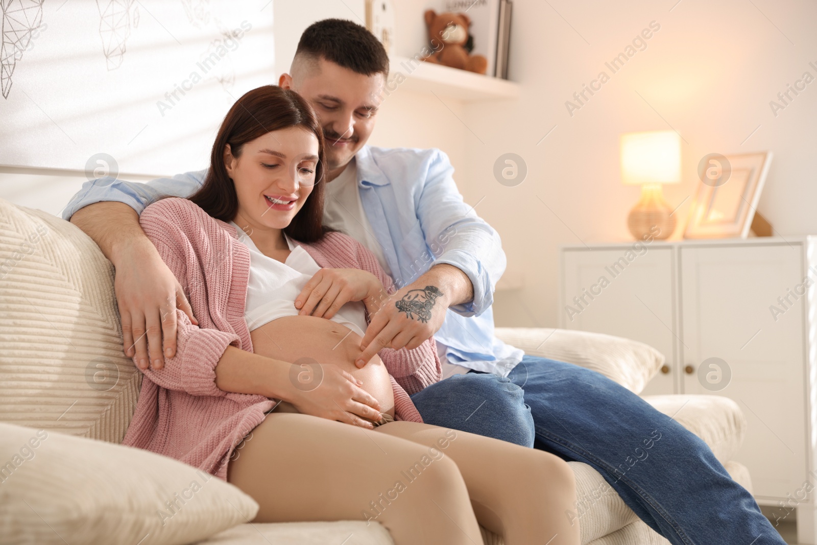 Photo of Pregnant woman and her husband on sofa at home