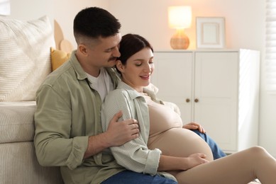 Photo of Pregnant woman and her husband on floor at home