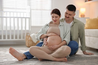 Photo of Pregnant woman and her husband on floor at home