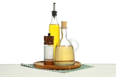 Photo of Salad dressings and salt on wooden table against white background