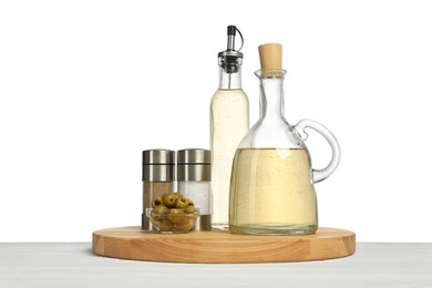 Photo of Salad dressings, olives and spices on wooden table against white background