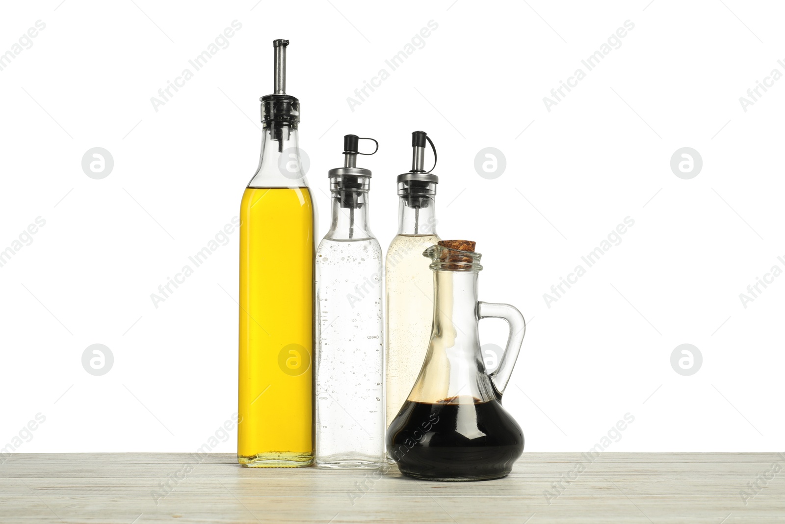 Photo of Oil and vinegars in bottles on wooden table against white background