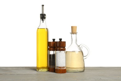 Photo of Salad dressings and spices on grey wooden table against white background